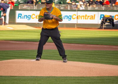 Baseball coach Chris Kyriacou throws the ceremonial first pitch at the Oakland Coliseum