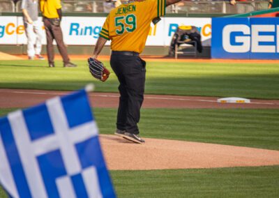 Baseball coach Chris Kyriacou throws the ceremonial first pitch at the Oakland Coliseum